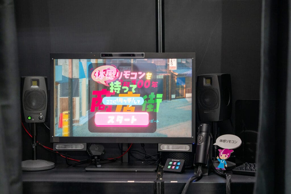 展示の1つ。立体視テレビと体験用のハンドルがおいてある